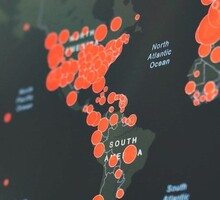 Imagem de parte de mapa que mostra casos de covid-19 na pandemia. A América aparece, e a América do Sul está mais em foco. Há muitos círculos vermelhos nos países, mostrando a incidência de casos. O Brasil possui o maior círculo da América Latina. Os Estados Unidos também estão aparentes e possuem uma grande quantidade de círculos por todo o território.