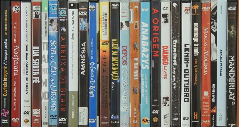 DVDs alinhados lado a lado, mostrando lombadas com os títulos, entre os quais: Nosferatu, 2001: uma odisseia no espaço, Rua Santa Fé, Sob o céu do Lìbano,  Anabazys,  A origem, Manderlay