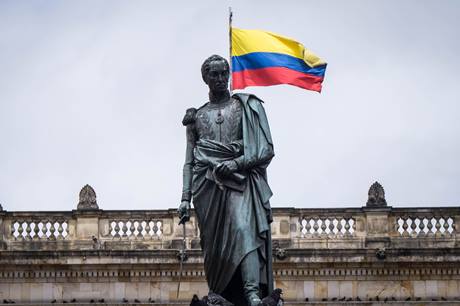 Estátua de Simon Bolivar, com bandeira da Colômbia ao fundo, em Bogotá