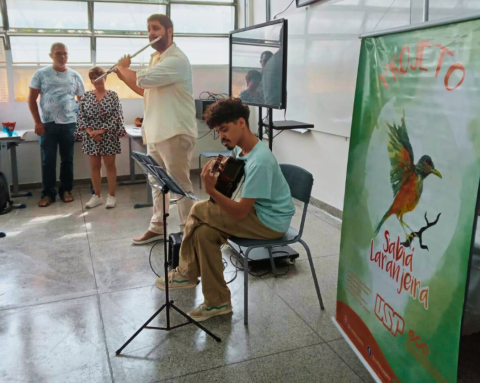 Dois jovens músicos se apresentam em uma sala de aula. Um deles está de pé e toca flauta; o outro está sentado em uma cadeira, de pernas cruzadas, e toca violão. Duas pessoas - um homem e uma mulher - os observam, de pé, ao fundo. Atrás dos músicos, uma lousa branca, um televisor e um banner, no qual se lê Projeto Sabiá Laranjeira.