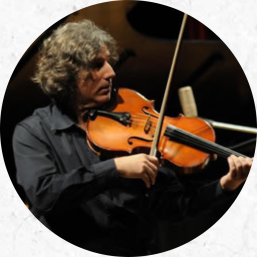 Foto de Marcelo Jaffé, um homem de pele branca, cabelos grisalhos e ondulados na altura do pescoço, tocando uma viola de arco. O instrumento está posicionado entre o seu queixo e tórax. Ele veste camisa preta. 