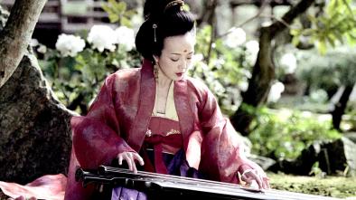 Foto colorida em ambiente externo, de uma mulher chinesa com roupas e maquiagens tradicionais da cultura chinesa