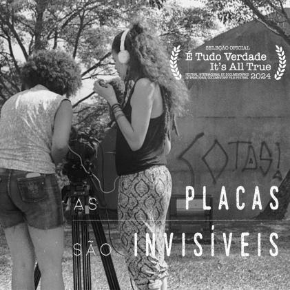 Arte digital do filme. No canto superior direito, o selo de seleção do Festival é Tudo Verdade 2024. No canto inferior direito, o título do filme, As Placas São Invisíveis. O fundo é composto por uma fotografia em preto e branco de duas jovens negras próximas a uma câmera sobre um tripé em um gramado. A da esquerda está de costas, tem cabelos escuros e crespos no estilo black power e sua uma regata clara estampada e bermuda jeans. Ela manuseia a câmera. A da esquerda está de perfil e usa um fone de ouvido conectado à câmera. Ela tem cabelos crespos longos com alguns dreads, usa regata preta e calça comprida estampada. Atrás delas há árvores e uma escultura de concreto com a palavra cotas pichada na cor preta.