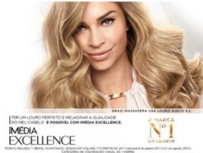Cartaz de uma campanha publicitária de produtos para o cabelo. A propaganda traz uma mulher loira e de sorriso sedutor encarando a câmera, com ênfase nos seus cabelos, que são lisos, sedosos e brilhantes. 