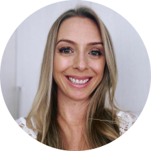 Foto de mulher branca sorrindo. Ela tem cabelos lisos, compridos e loiros, olhos castanhos e usa uma blusa branca. O fundo é branco.