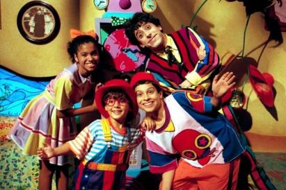 Foto das personagens de Castelo Rá-Tim-Bum fazendo pose e olhando para a câmera. Nino, Pedro, Zeca e Biba usam roupas coloridas e estão em um dos cenários típicos do programa