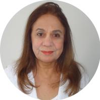 Foto de uma mulher de pele clara, de cabelos longos, lisos e castanhos claros, olhos castanhos e roupa branca. O fundo da foto é branco.