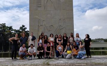 Foto colorida em ambiente externo, dos alunos estrangeiros da ECA em frente ao relógio da Praça do Relógio na USP