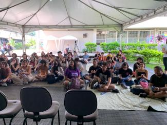 Foto colorida em ambiente externo, dos calouros da ECA sentados. 