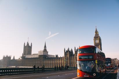 Foto colorida em ambiente externo, de um típico ônibus de dois andares britânico, e, ao fundo, a famosa construção o Big Ben.