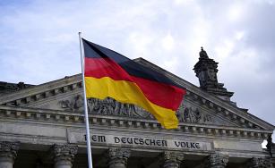 Bandeira da Alemanha em frente a frontão do prédio do Parlamento Alemão