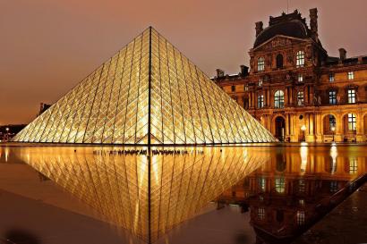 Foto colorida em ambiente externo, da construção de vidro em frente ao museu do Louvre