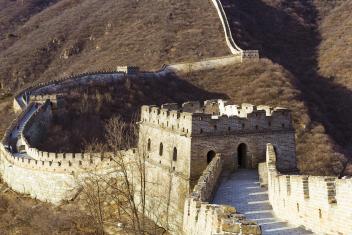 Muralha da China em terreno com vegetação rasteira e amarelada