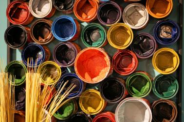 Foto colorida de latas de tintas coloridas abertas.
