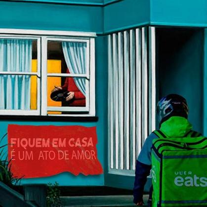 Motoboy da UberEats encontra-se em frente à uma residência com a placa &quot;Fiquem em casa. É um ato de amor&quot;.