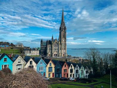 Foto colorida em ambiente externo, de casas irlandesas em frente a uma catedral.