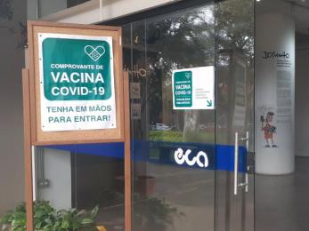 Foto colorida mostra mural na entrada do prédio principal da ECA com cartaz com os seguintes dizeres: &quot;Comprovante de vacina covid-19. Tenha em mãos para entrar!&quot; 