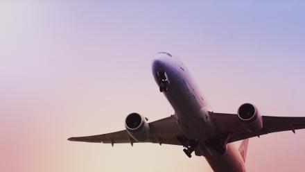 Foto colorida em ambiente externo, de um avião erguendo voo