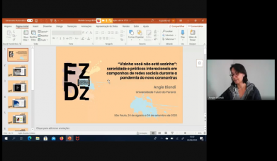 Imagem da transmissão ao vivo do evento Fazendo e Desfazendo Gênero. À esquerda, slides com o logo do evento e o título do trabalho de pesquisa: "Vizinha você não está sozinha: sororidade e práticas interacionais em campanhas de redes sociais durante a pandemia do novo coronavírus". À direita, a imagem da pesquisadora Angie Biondi faz a apresentação. Ela é uma mulher de pele branca, cabelos escuros na altura do pescoço e óculos de aro vermelho.