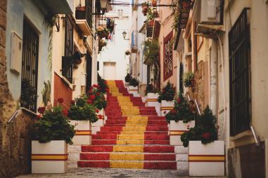 Foto colorida em ambiente externo, de uma escada pintada com as cores da bandeira da Espanha