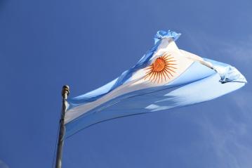 Foto colorida, em ambiente externo, da bandeira da Argentina tremulando