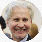 Foto de homem branco sorrindo. Ele tem cabelos brancos e curtos, barba e bigode brancos.