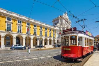 Bonde elétrico vermelho em frente à prédio amarelo em Lisboa