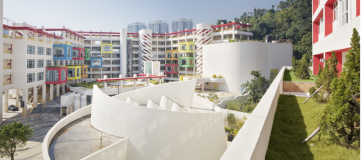 Foto colorida em ambiente externos, de prédios pintados de branco com janelas coloridas no campus da Universidade de São José
