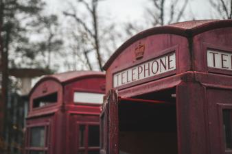 Foto colorida em ambiente externo, de uma cabine telefônica tradicional do Reino Unido