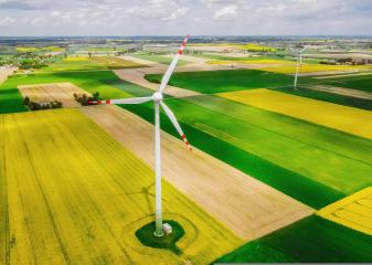 Foto colorida em ambiente externo, de um moinho de vento em um campo verdejante