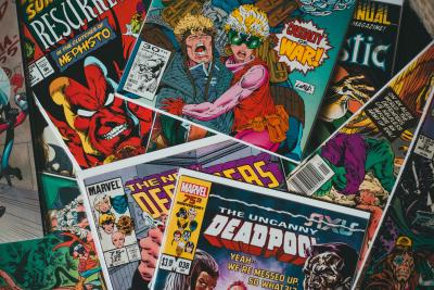 Foto das capas de várias revistas em quadrinho da Marvel, como Deadpool, espalhadas e sobrepostas. 