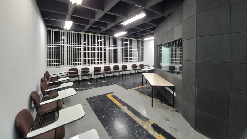 Sala com carteiras escolares, em semi-circulo, ao redor do estúdio de gravação de rádio - - abril de 2022