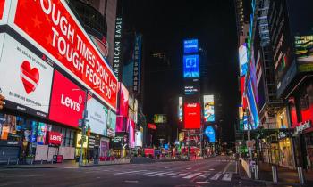 Imagem de rua com muitos prédios com anúncios publicitários luminosos, mas sem qualquer pessoa. A foto foi tirada à noite.