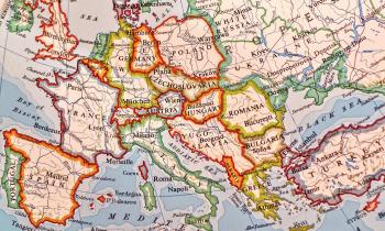 Mapa que mostra a Europa central e o leste europeu, além de partes da Grã-Bretanha, do sul e do norte da Europa. O mar é azul e as fronteiras dos países estão identificadas por contornos coloridos em tons de laranja, amarelo, verde e vinho. Na porção direita do mapa, parte da Rússia e da Turquia aparecem. 