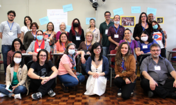 Foto de grupo de funcionárias e funcionários da ECA posando; à frente, as funcionárias estão sentadas; atrás delas outras funcionárias estão sentadas em carteiras escolares; ao fundo, em pé, os demais funcionários e funcionárias, além dos dois ministrantes do curso.