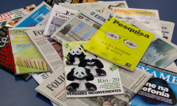 Foto de vários jornais e revistas de capas coloridas em cima de uma superfície azul escura.