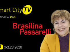 num fundo preto, aparecem, à direita, uma imagem da entrevistada (uma mulher branca, de cabelos curtos e loiros, que veste um blazer amarelo e uma blusa roxa. Do lado esquerdo, está escrito o nome da entrevistada, a data da entrevista e o nome do canal.