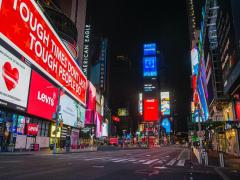 Imagem de rua com muitos prédios com anúncios publicitários luminosos, mas sem qualquer pessoa. A foto foi tirada à noite.