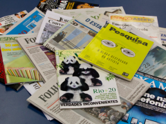 Foto de vários jornais e revistas de capas coloridas em cima de uma superfície azul escura.