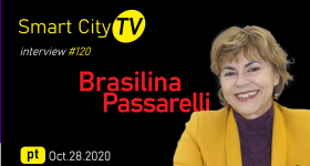 num fundo preto, aparecem, à direita, uma imagem da entrevistada (uma mulher branca, de cabelos curtos e loiros, que veste um blazer amarelo e uma blusa roxa. Do lado esquerdo, está escrito o nome da entrevistada, a data da entrevista e o nome do canal.